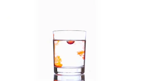 Tree small drops of orange red ink's dripping into pure water glass Stock Footage 152994545