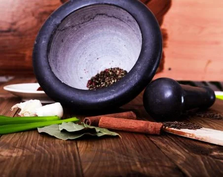 Tree spoons with spices and a bundle of herbs, mortar and pestle Stock Photos