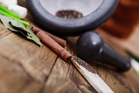 Tree spoons with spices and a bundle of herbs, mortar and pestle Stock Photos