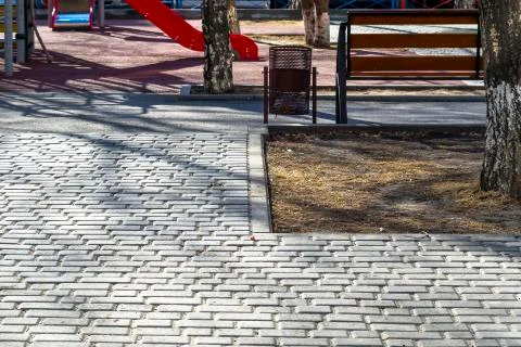 Tree Trunk, Empty Bench at the Paved Kids Playground Area in the Park on a Sp Stock Photos
