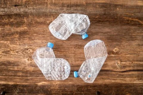 Tree wasted plastic bottle in shape of the symbol of recycling on wooden Stock Photos