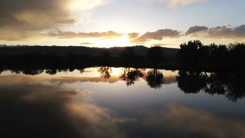 Trees and clouds over lake - Drone camera moves forward and up Stock Footage 137887244