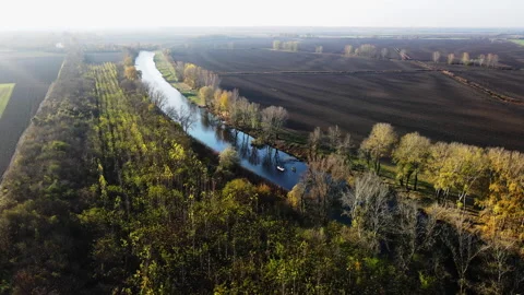 Trees and fields surrounding a river in autumn, fisherman in boats on lake Stock Footage 263189928