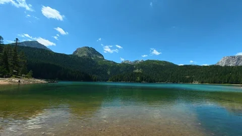 Trees line the shore, adding lush green texture. Black Lake, Montenegro 库存影片 342967833