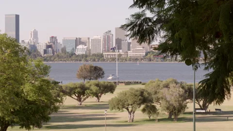 Trees in park with large Australian flag by river - city in background Stock Footage 146766791