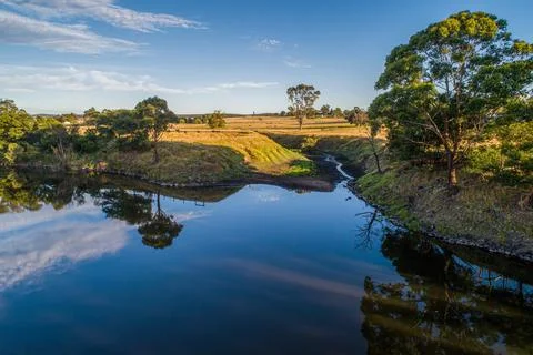 Trees reflecting in smooth water surface at sunset in Australia Stock Photos