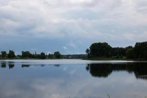 Trees by the river under a dark cloudy sky Stock Photos