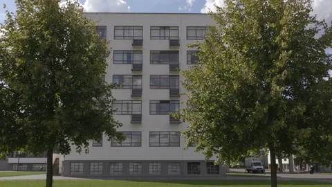 Trees on the wind with Bauhaus facade in the background Stock Footage 83633350