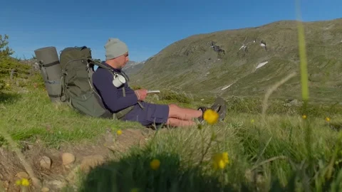 A trekker looks at his map, compass and the mountains in Norway Stock Footage 156786913