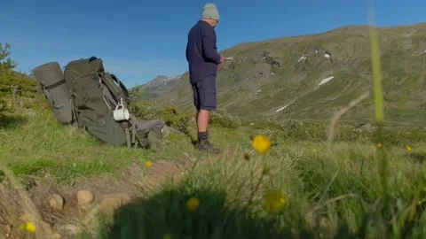 A trekker looks at his map, compass and the mountains in Norway Stock Footage 156787733
