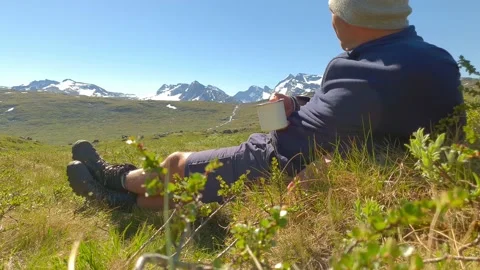 Trekker rests with coffee infront of a mountain range in Norway Stock Footage 156787936