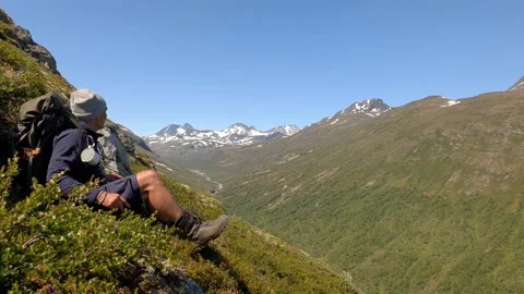 Trekker sits down at mountainside and enjoys the view in Norway Stock Footage 156786795