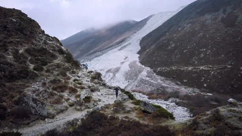 Trekkers walking on a himalayan mountain trail next to a glacier Stock Footage 335495707