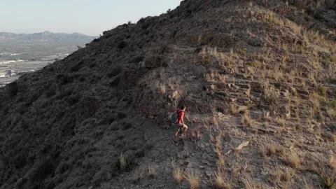 Trekking off the beaten path, a man in shorts and a red shirt with trekking.. Video stock 283972613
