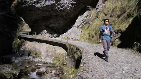 Trekking - Boy walking on paved trail through a gorge Stock Footage 49045531