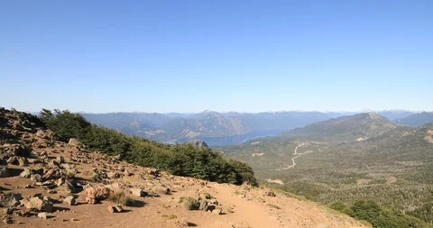 Trekking, going down the mountain summit. Panoramic view of lake and woods. Video stock 126733049