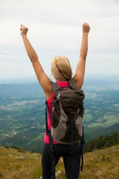 Trekking - woman hiking  in mountains on a calm sumer day being happy and ris Stock Photos
