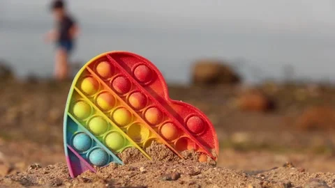 A trend rainbow bubble toy - Pop it. Beach, sea and walking kid on  background. Stock Footage 156983144