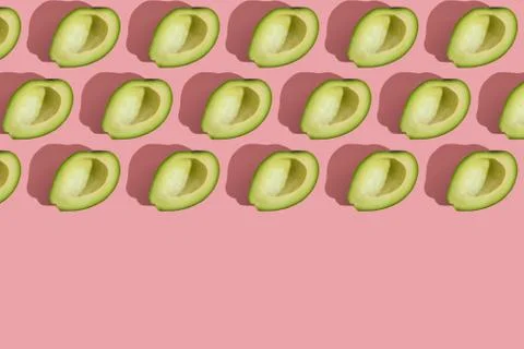 Trending style pattern of half seedless green avocado on pink background with Stock Photos