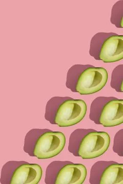 Trending style pattern of half seedless green avocado on pink background with Stock Photos
