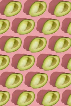 Trending style pattern of half seedless green avocado on pink background with Stock Photos