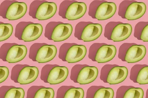 Trending style pattern of half seedless green avocado on pink background with Stock Photos