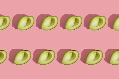 Trending style pattern of half seedless green avocado on pink background with Stock Photos