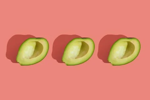Trending style pattern of half seedless green avocado on pink background with Stock Photos