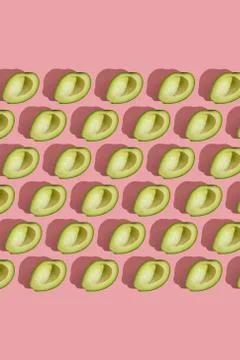Trending style pattern of half seedless green avocado on pink background with Stock Photos