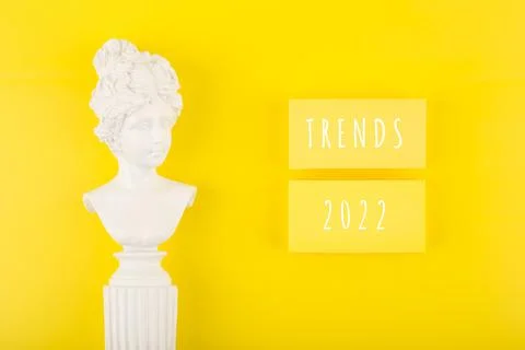 Trends 2022 written on rectangles on bright yellow background next to woman Stock Photos