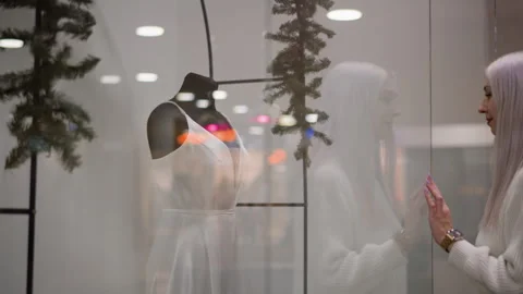 Trendsetter viewing sleeveless long dinner gown behind boutique glass Stock Footage 316828698