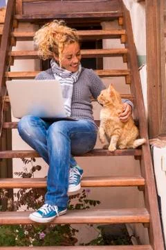 Trendy adult pretty woman with mobile computer laptop outside home and a beau Stock Photos
