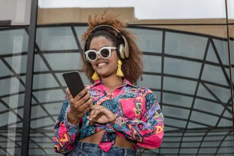 Trendy black female in headset using social media on cellphone Stock-Fotos