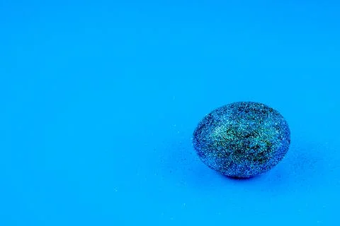 Trendy easter background with shiny blue colored egg and with glitters around Stock Photos