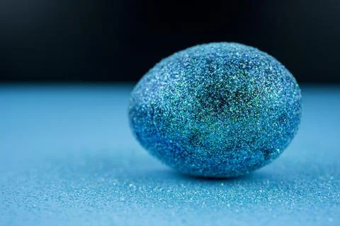 Trendy easter background with shiny blue colored egg and with glitters around Stock Photos