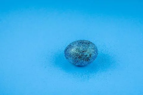 Trendy easter background with shiny blue colored egg and with glitters around Stock Photos