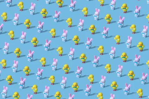 Trendy Easter pattern made of rabbits hares and chicken toys on blue background Stock Photos