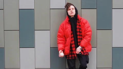 Trendy guy standing at the wall and throws up a ball 库存影片 123863840
