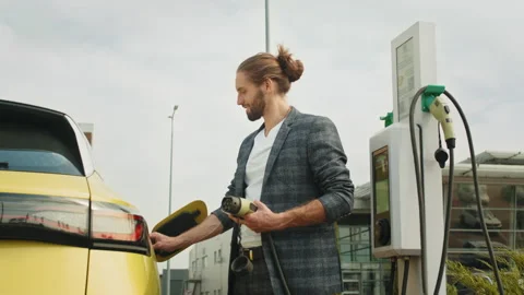 Trendy handsome man dressed in a plaid suit holding smartphone while charging Stock Footage 235359280