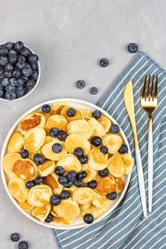Trendy home breakfast with tiny pancakes and blueberry on gray concrete backg Foto stock