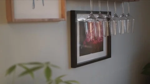 Trendy home decor including hung photos, wine glass holder, indoor plants Stock-Footage 128317263