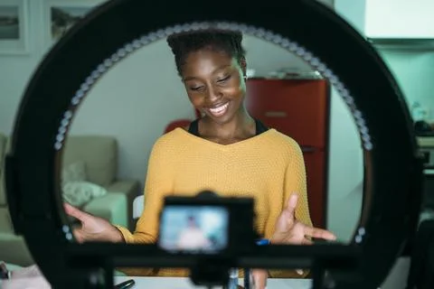 In a trendy indoor setting, a vlogger is utilizing a ring light for creating Foto stock