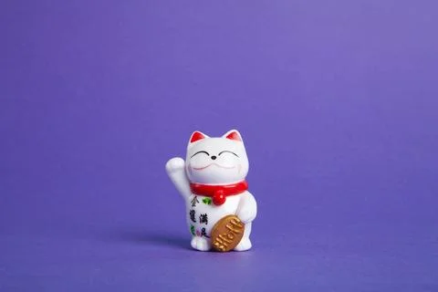 A trendy Maneki-neko plastic cat on violet background Stock Photos