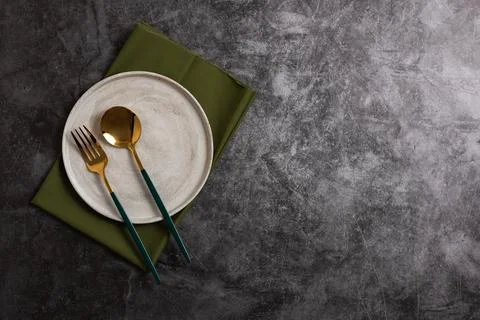 Trendy minimal tableware setting with the gray plate and golden cutlery Stock Photos