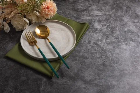 Trendy minimal tableware setting with the gray plate and golden cutlery Stock Photos