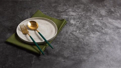 Trendy minimal tableware setting with the gray plate and golden cutlery Stock Photos