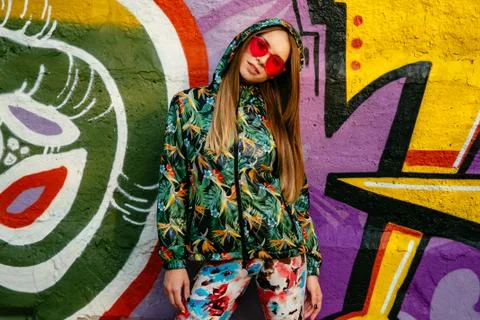 Trendy model in stylish clothes posing near the wall with drawing Stock Photos