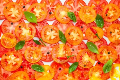 Trendy pattern of sliced ripe red, yellow and orange tomatoes decorated green 写真素材