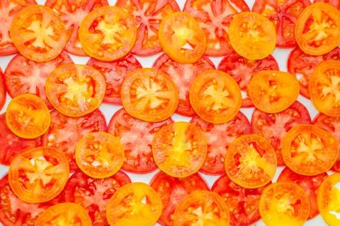 Trendy pattern of thin sliced ripe red, yellow and orange tomatoes on white b Fotos de archivo