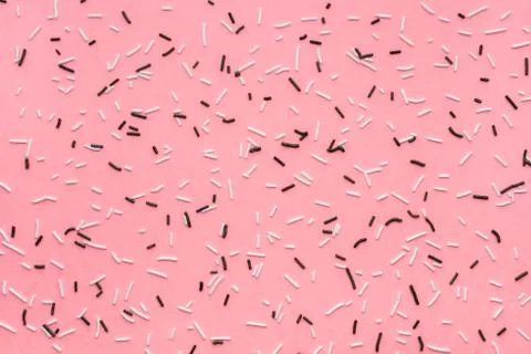 Trendy pattern of white and black sprinkles over pink background, sugar sprin Foto stock